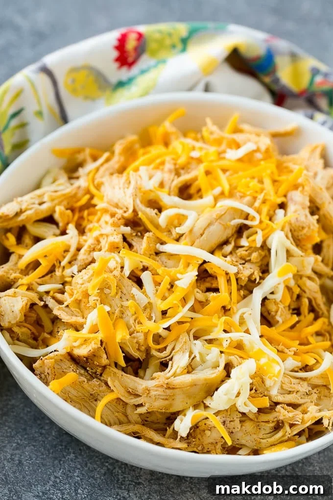 A bowl filled with a seasoned mixture of shredded chicken and melted cheeses, the delicious filling for chicken taquitos.