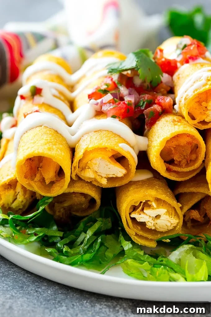 Serving Baked Chicken Taquitos with Toppings A vibrant plate of crispy chicken taquitos arranged on a bed of fresh lettuce, generously topped with a dollop of sour cream and bright pico de gallo.