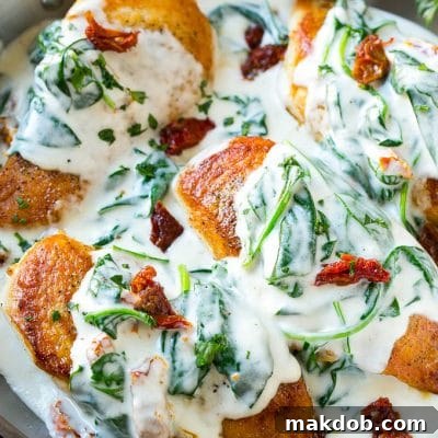 Sun dried tomato chicken covered in a creamy spinach sauce in a frying pan.