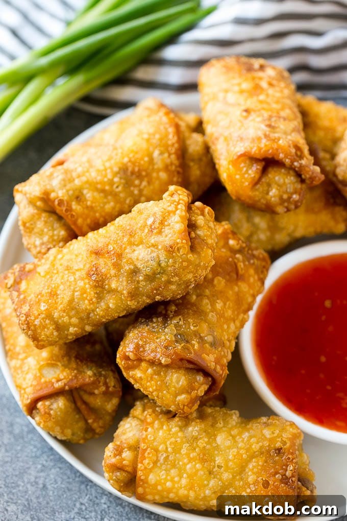Homemade Egg Rolls | Chinese Egg Rolls | Pork Egg Rolls | Egg Roll Recipe #eggrolls #appetizer #dinneratthezoo#chinesefood A pile of fried homemade egg rolls with dipping sauce.