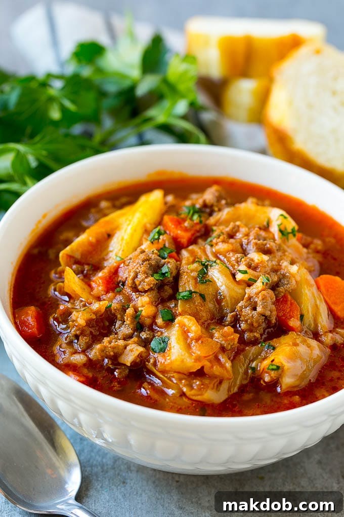 A bowl of unstuffed cabbage soup with bread and parsley.