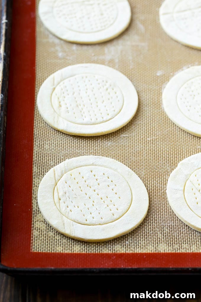 Luscious Fruit Cream Cheese Danish 3 Puff pastry rounds are neatly arranged on a baking sheet, forming the base for homemade cream cheese danishes before the filling is added.