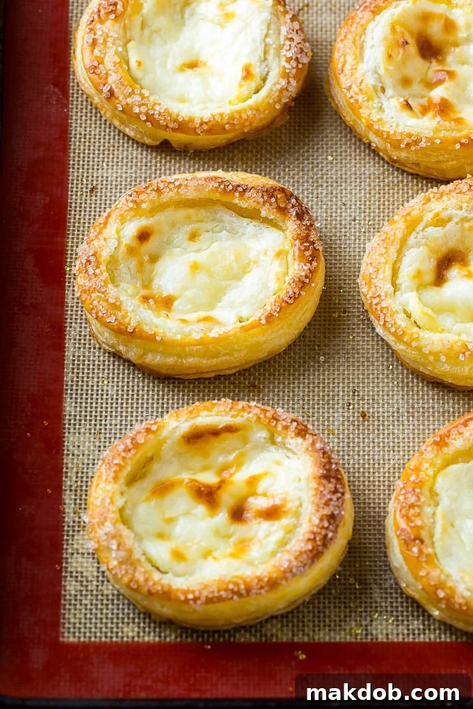 Luscious Fruit Cream Cheese Danish 5 A batch of freshly baked cream cheese danishes, golden brown and puffed, are cooling on a wire rack after being removed from the oven.