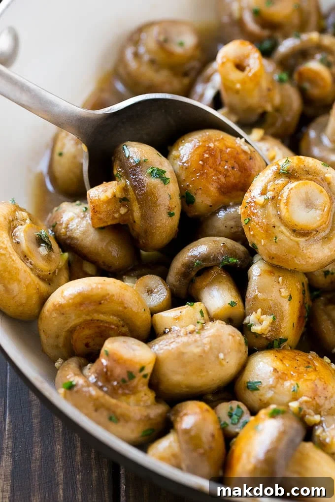 A pan of sauteed garlic mushrooms with a serving spoon.