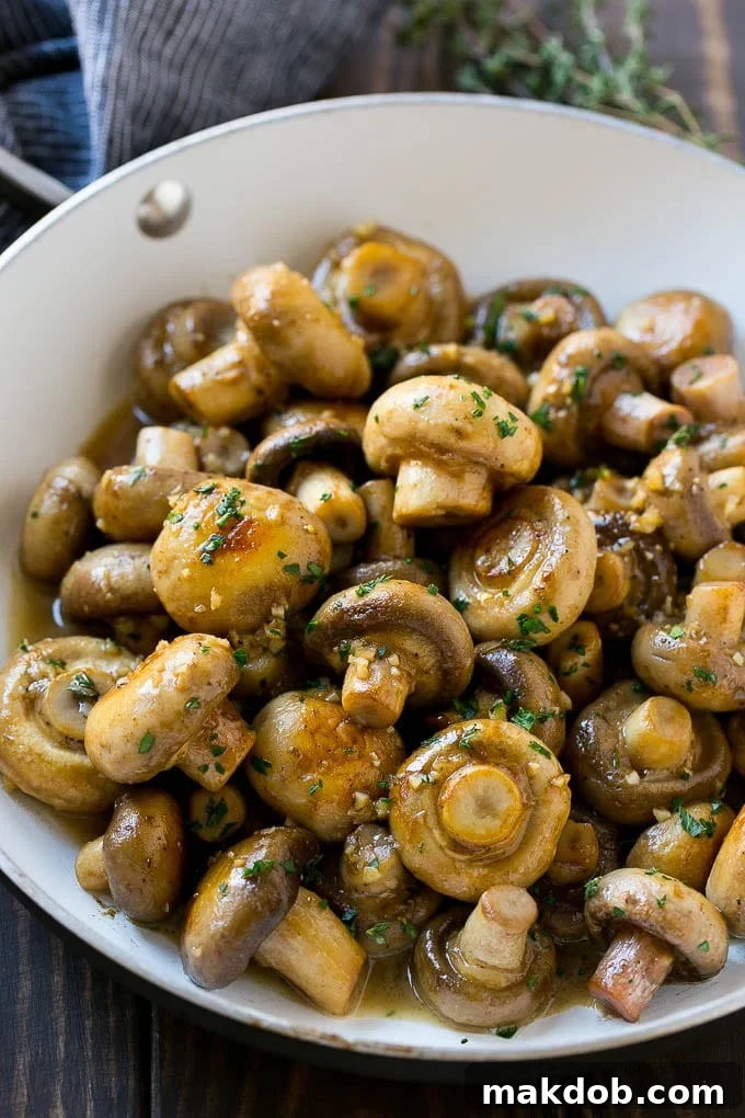 A pan full of cooked mushrooms coated in garlic butter.