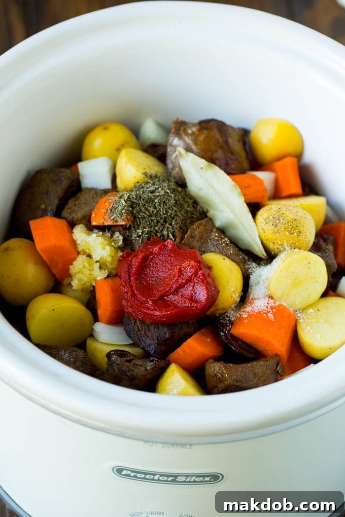 Hearty Slow Cooker Beef Stew 4 A slow cooker brimming with rich beef stew ingredients, including beef, vegetables, tomato paste, and aromatic herbs.