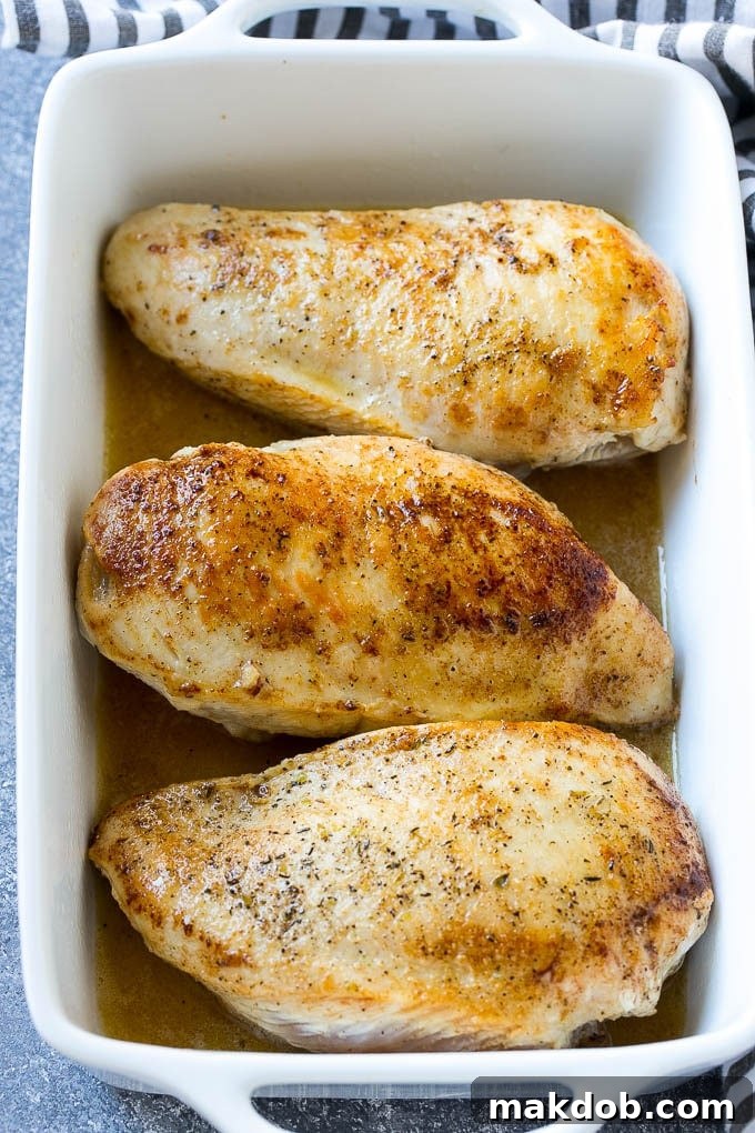 Succulent chicken breasts submerged in a vibrant lemon butter sauce within a baking dish, ready for oven roasting to perfection.