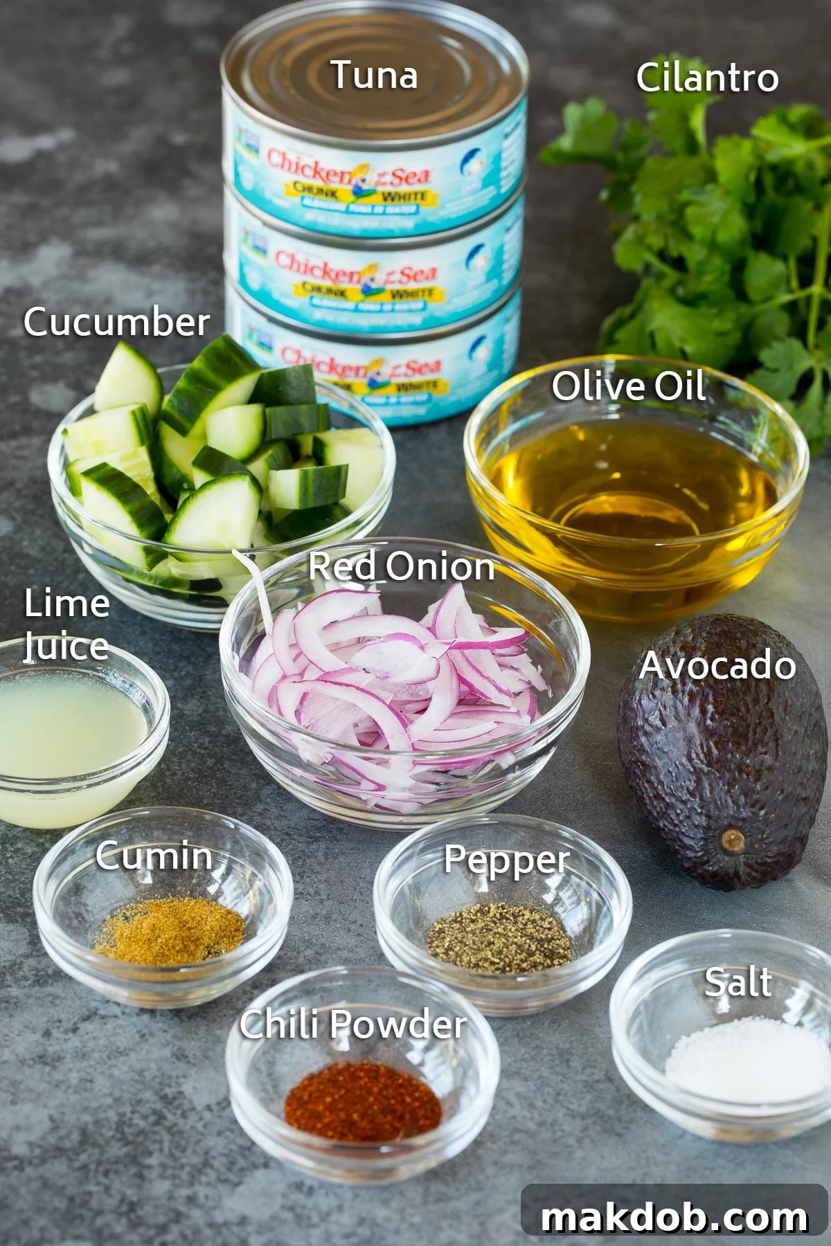 Various bowls of fresh ingredients including vibrant lime juice, chopped vegetables, aromatic seasonings, and several cans of tuna, ready for assembly.