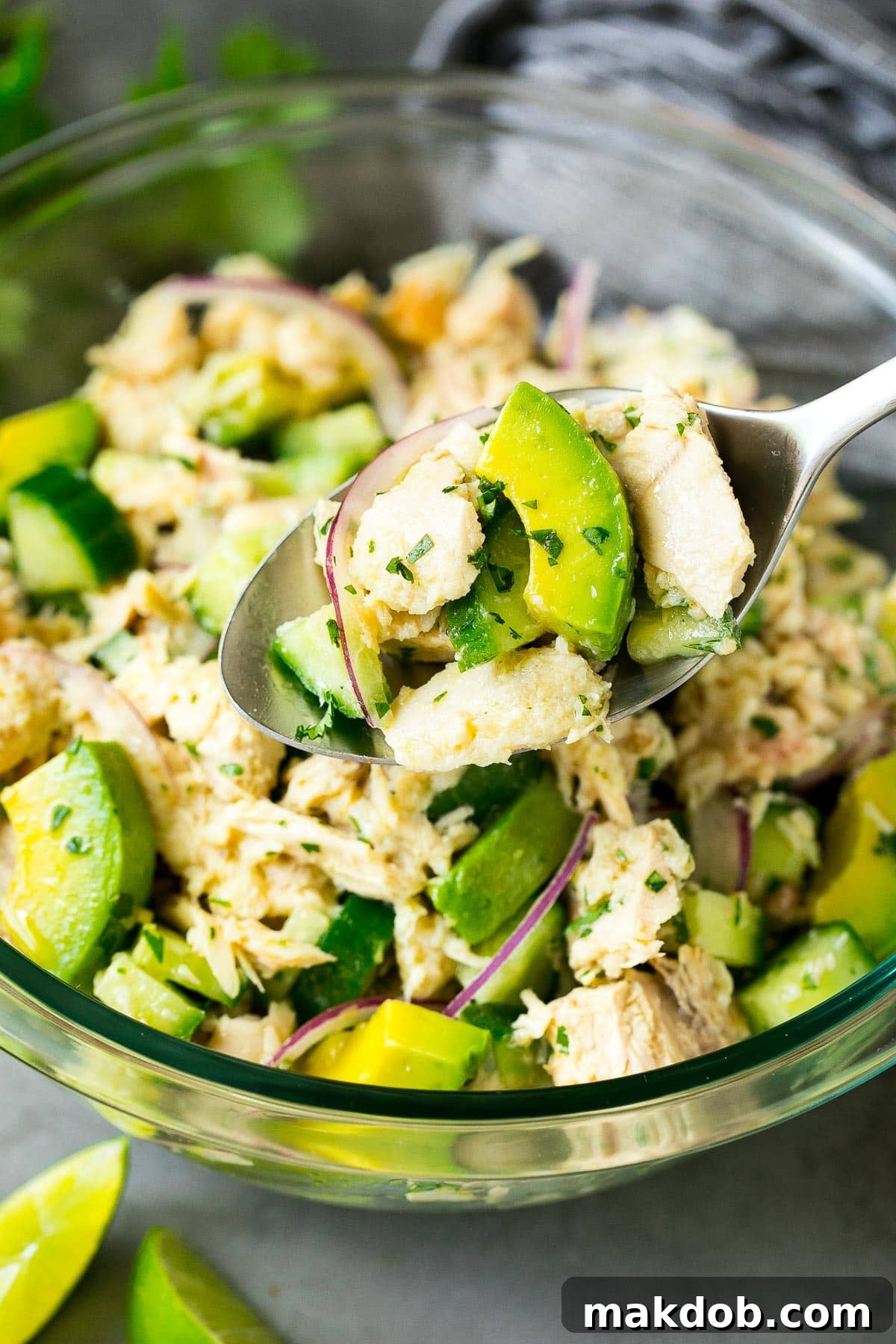 A spoon delicately scooping up a portion of the creamy avocado tuna salad, highlighting its rich textures and fresh appeal.