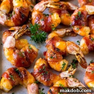 Bacon wrapped shrimp in a sweet and savory glaze, garnished with parsley.