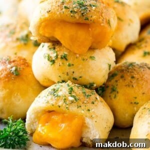 A stack of cheese bombs with melted cheddar cheese oozing out of them.