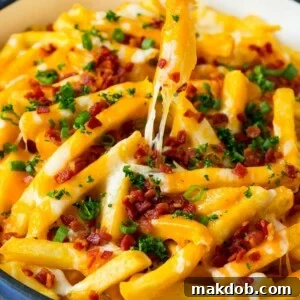 A skillet of cheese fries with bacon, and a hand reaching for one.