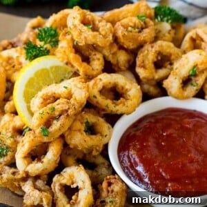 Fried calamari with lemon wedges and a side of cocktail sauce.