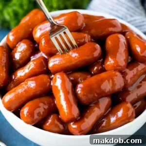 A bowl of crockpot little smokies with a fork in it.