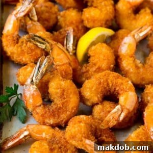 Fried shrimp on a sheet pan garnished with parsley and lemon.