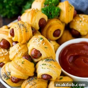 A plate of pigs in a blanket served with ketchup.