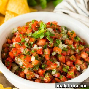 A bowl of salsa fresca served with chips.