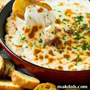 A crouton pulling out a serving of cheesy shrimp scampi dip.