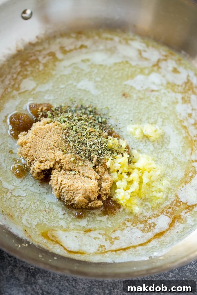 Close-up of melted butter, brown sugar, fragrant Italian herbs, and minced garlic simmering in a skillet, forming the base of the rich sauce for pork chops.
