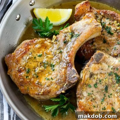 Brown sugar pork chops with garlic, butter and herbs in a frying pan.