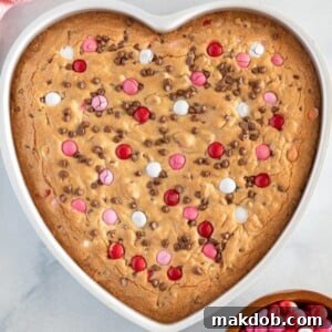 An image of a heart shaped large cookie with red and pink M&M candies.