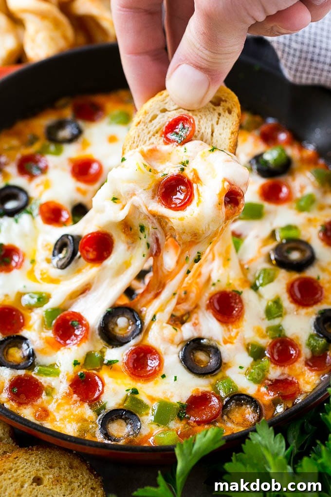 Gooey Pepperoni Pizza Dip Pizza dip showcasing layers of melted cheese and various toppings, ready to be served with baguette slices.