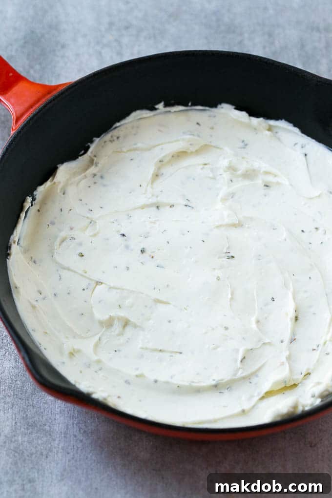 Cream Cheese Base for Pizza Dip A smooth layer of seasoned cream cheese forming the base of the pizza dip.