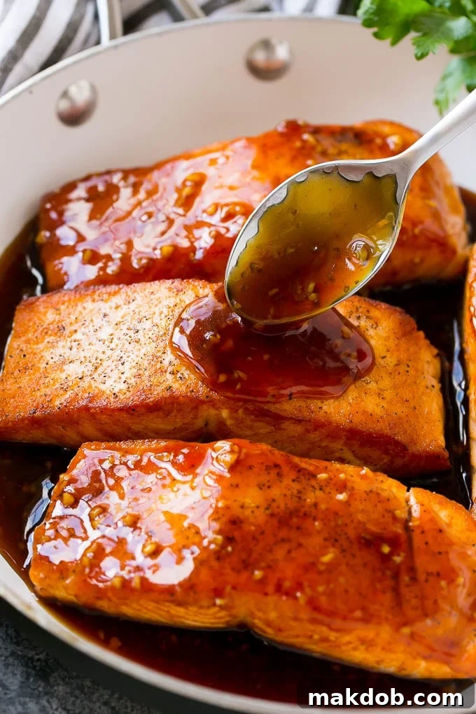 Honey Garlic Salmon Recipe | Asian Salmon Recipe | Healthy Salmon Recipe #salmon #fish #seafood #healthy #dinner #dinneratthezoo A spoon pouring sauce on top of salmon fillets.