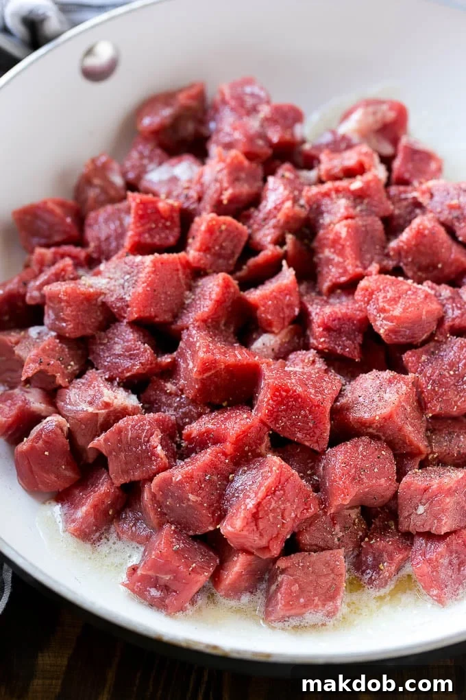 Cubes of raw beef seasoned with salt and black pepper, ready for searing.
