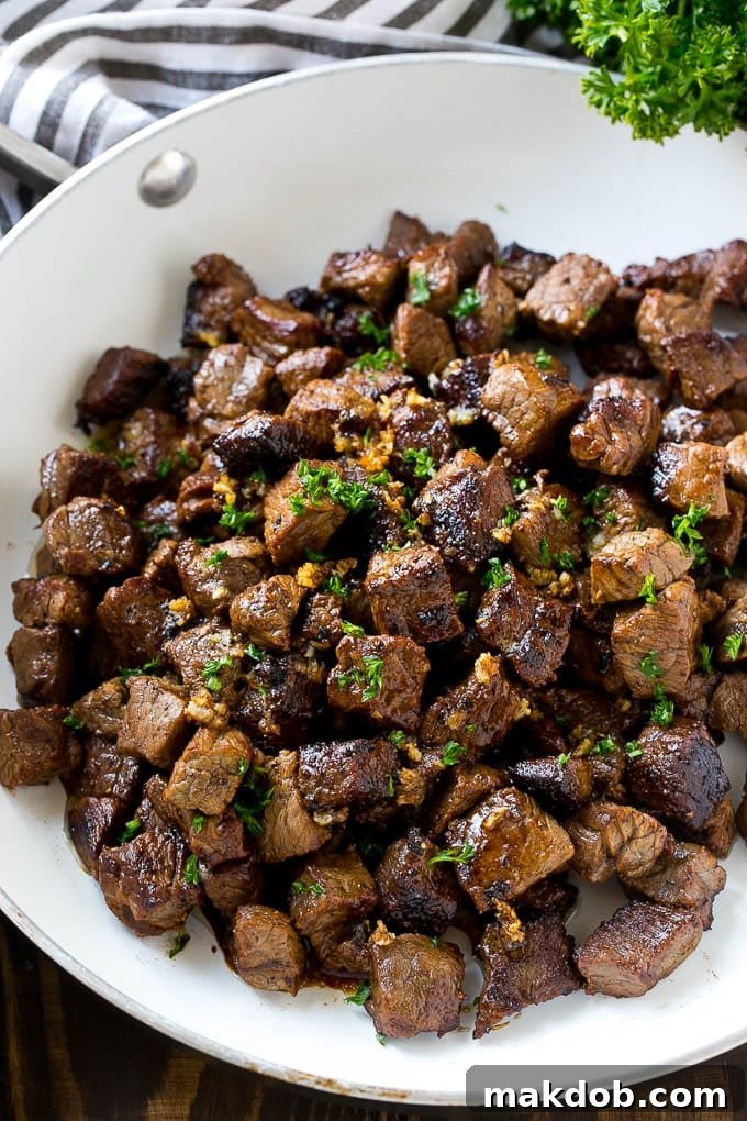 A frying pan of beef cubes tossed in garlic butter, freshly cooked.