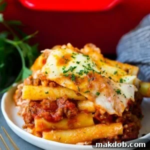 A serving of baked ziti with meat sauce and ricotta cheese, glistening with flavor.
