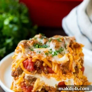 A generous slice of million dollar spaghetti casserole, topped with melted cheese.