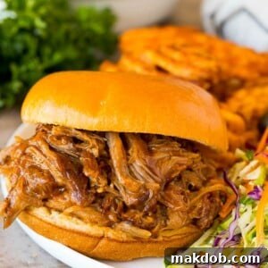 Instant Pot pulled pork on a sandwich with a side of crispy fries and coleslaw.