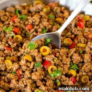 A pan of savory picadillo with a serving spoon.