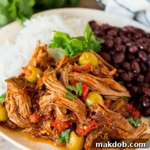 A plate of traditional ropa vieja served with rice and black beans.