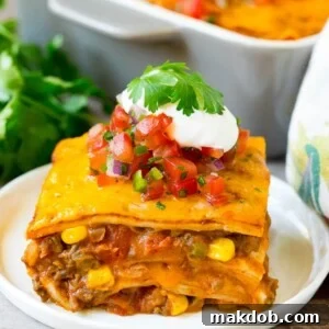 A slice of taco lasagna topped with fresh salsa, sour cream, and cilantro.