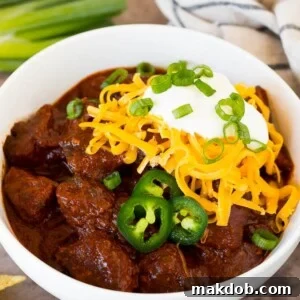 A bowl of hearty Texas chili topped with cheese and sour cream.