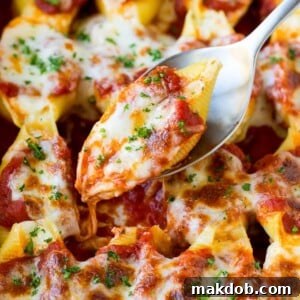 A spoon holding up stuffed shells filled with creamy cheese.