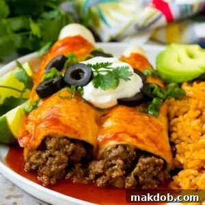 A plate of beef enchiladas topped with sour cream, olives, and green onions.
