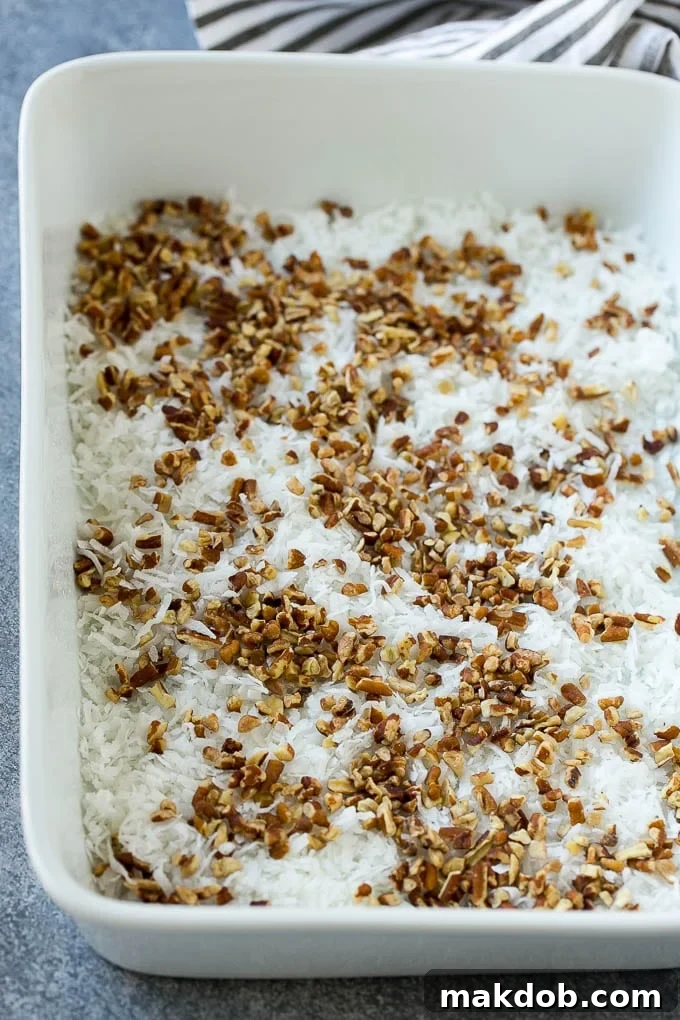 Coconut and pecans layered evenly into a 9x13 inch cake pan, ready for the batter.