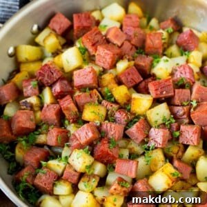 A savory plate of corned beef hash, featuring diced corned beef, tender potatoes, and caramelized onions, garnished with fresh herbs, ideal for a hearty breakfast or brunch.