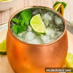 An Irish mule drink in a copper mug topped with a lime and mint sprig.