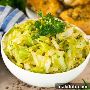 A bowl of vibrant sauteed cabbage, lightly cooked with butter, onions, garlic, and fresh herbs, topped with fresh parsley for garnish.