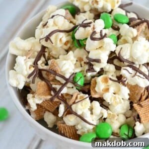 A delightful image of St. Patrick's Day s'mores snack mix, featuring ooey gooey marshmallow-covered popcorn, graham crackers, and chocolate, all in a festive bowl.