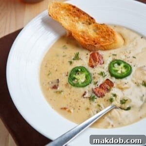 A rustic bowl of creamy ale and cheddar soup, rich with flavor and topped with a golden, toasted crust of bread for added texture.