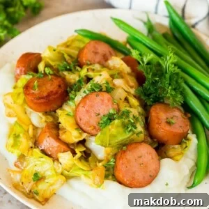 A plate of cabbage and sausage served over mashed potatoes with green beans.