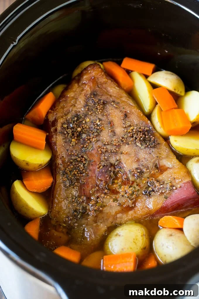 Slow Cooker Corned Beef Recipe | Crock Pot Corned Beef | Corned Beef and Cabbage #beef #cornedbeef #cabbage #potatoes #carrots #stpatricksday #irish #dinneratthezoo A seasoned brisket with potatoes and carrots in a slow cooker.