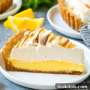 A slice of lemon meringue tart with creamy lemon filling and brown sugar meringue topping.