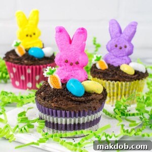 Chocolate cupcakes beautifully decorated with Peeps and colorful jellybeans, perfect for an Easter celebration.