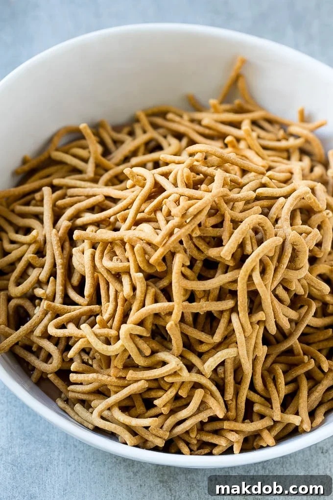 Birds Nest Cookies | Chow Mein Noodle Cookies | Easter Cookies | No Bake Cookies #cookies #easter #nobake #chocolate #dessert #dinneratthezoo Chow mein noodles being stirred into a bowl of melted chocolate and butterscotch.